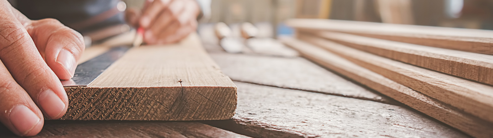 Carpenter working with equipment on wooden table in carpentry sh